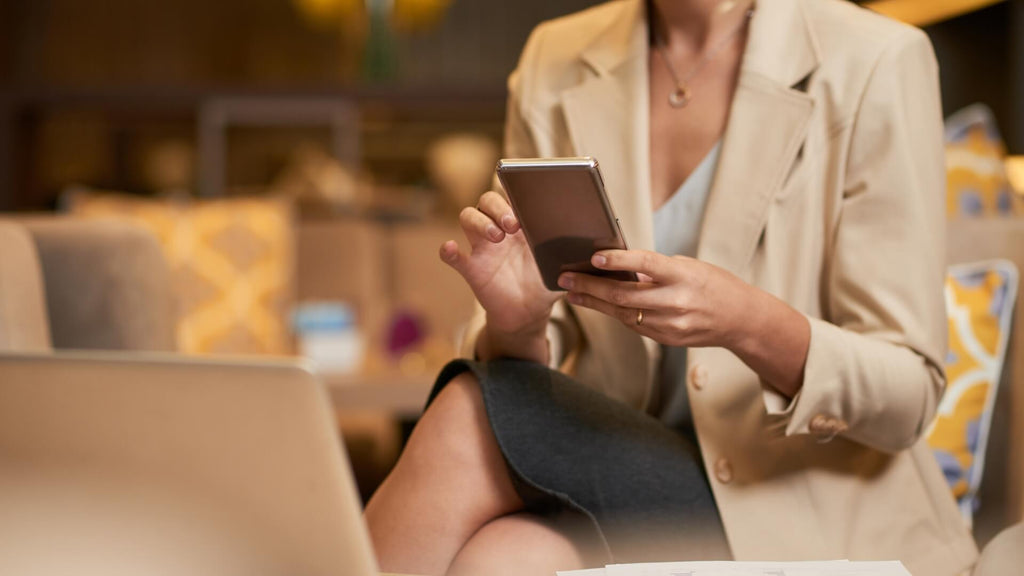 usinesswoman using a smartphone and laptop, symbolizing the integration of AI tools in transforming jewelry business operations.