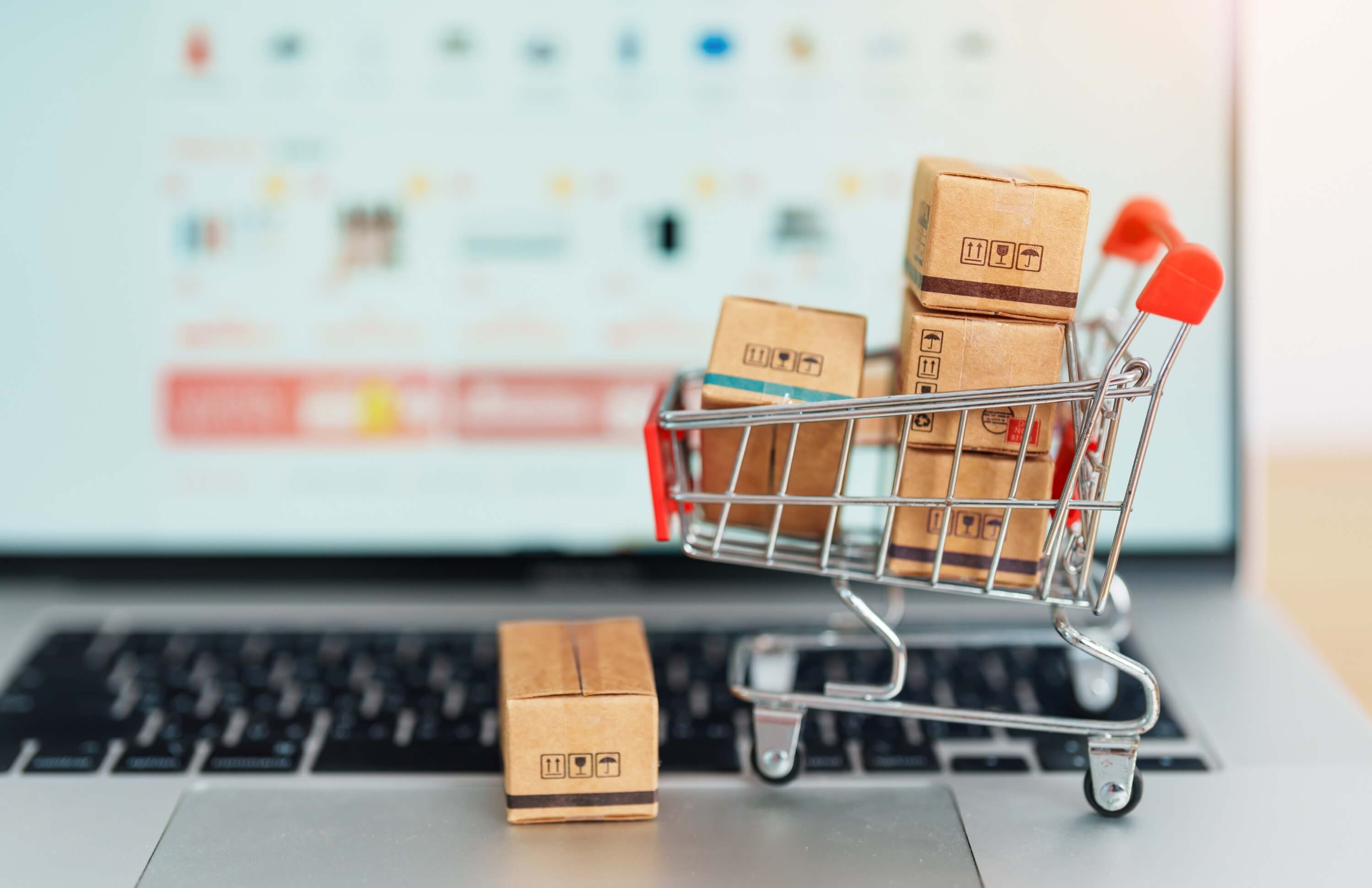 Mini shopping cart filled with boxes on a laptop keyboard, representing recovering abandoned carts and boosting sales.