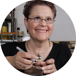 Estelle Vernon, jewelry designer, crafting a new piece in her studio, smiling