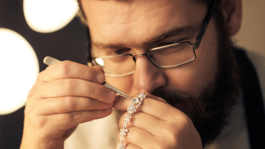 Jeweler closely inspecting a diamond necklace, symbolizing the focus on craftsmanship and the need for expert e-commerce support.