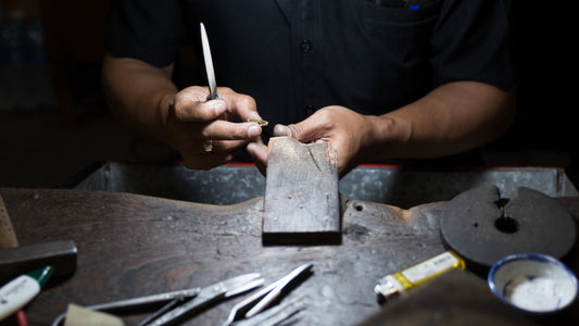 Jeweler meticulously crafting a piece of jewelry at a workbench, surrounded by tools, highlighting the art of handmade jewelry craftsmanship.