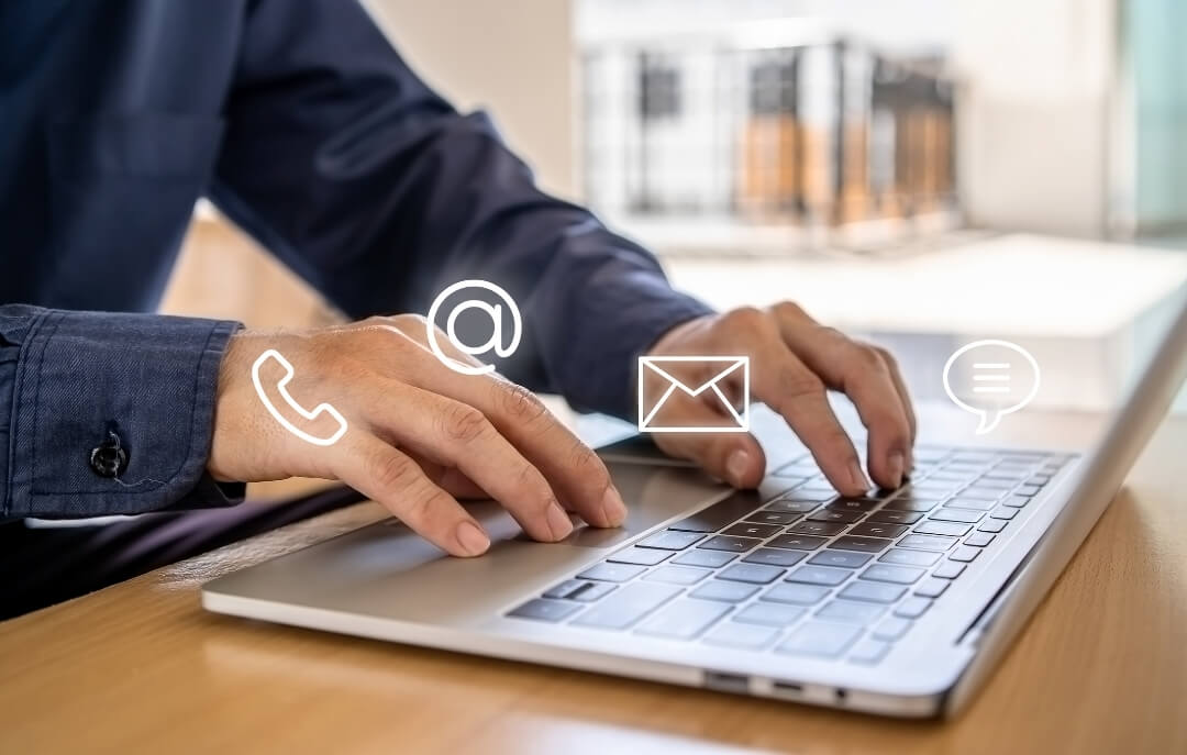 Hands typing on a laptop with communication icons overlay, symbolizing multi-channel customer support.