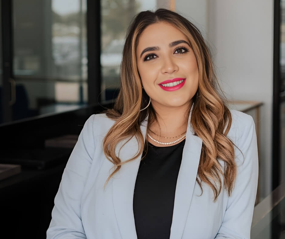 Seema Patel in her office wearing a light blue blazer and pearl necklace