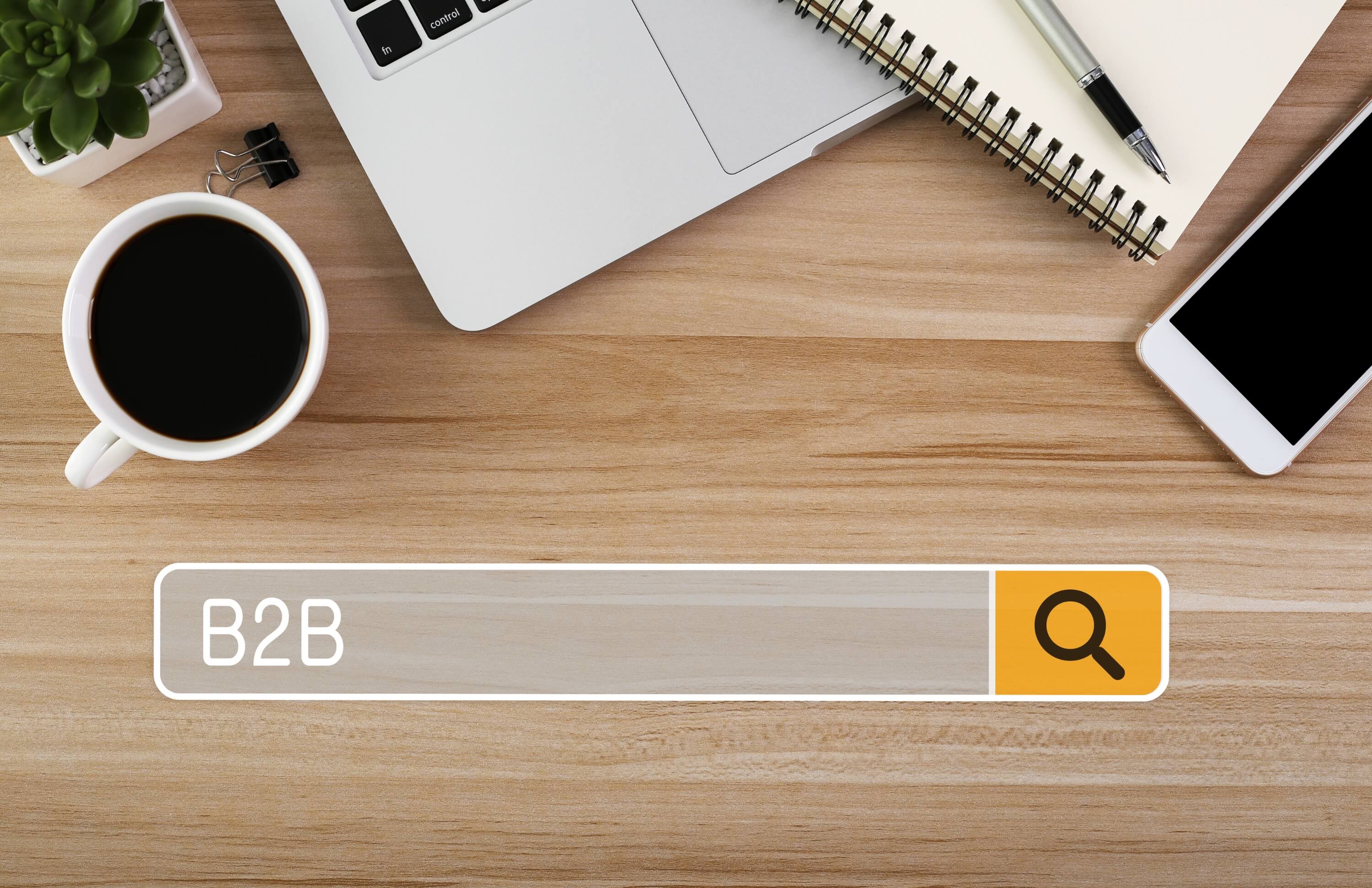 Search bar with B2B text on a wooden desk setup for e-commerce business.