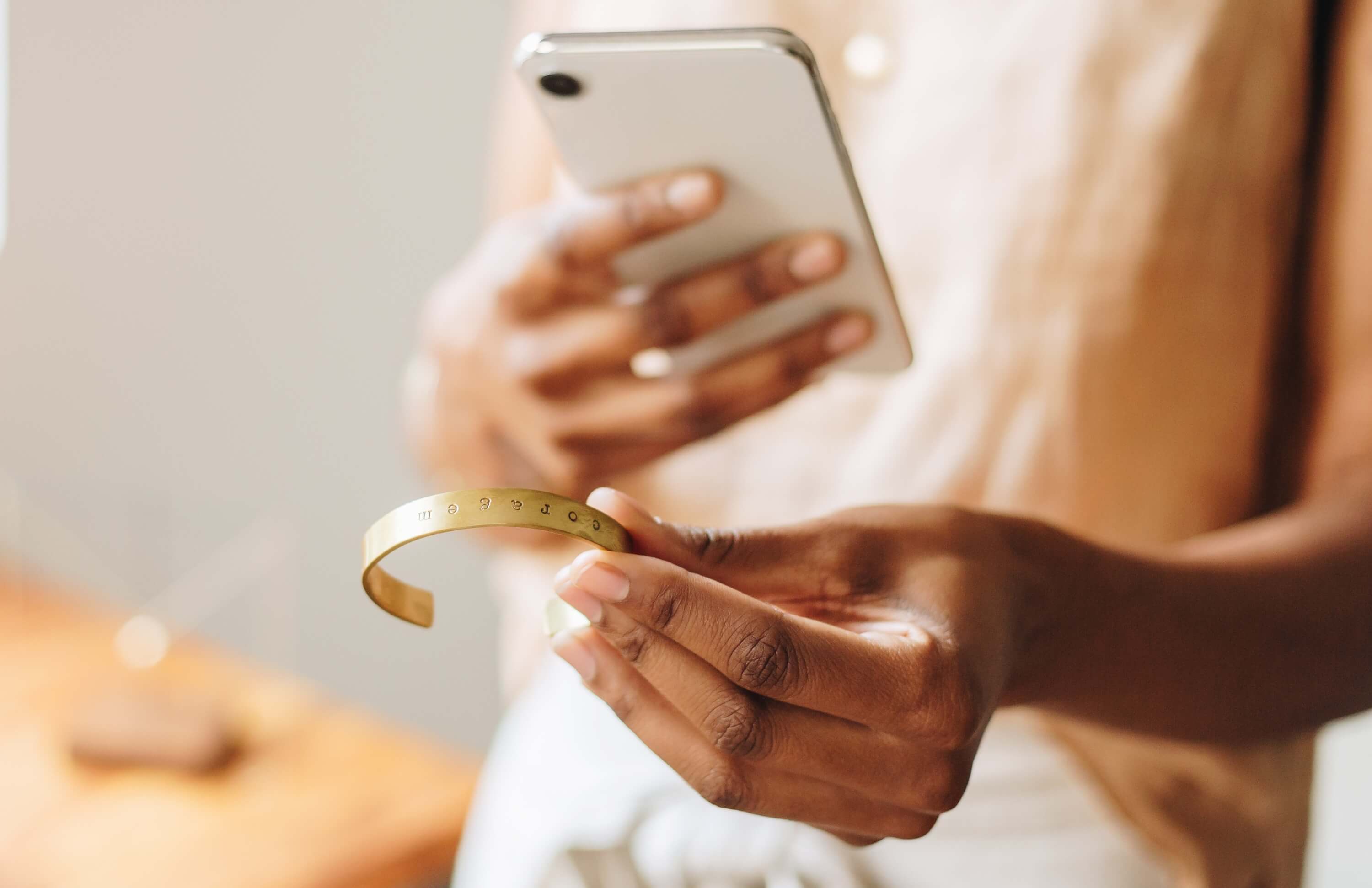 Hands holding a smartphone to photograph a jewelry piece, showcasing product photography strategies