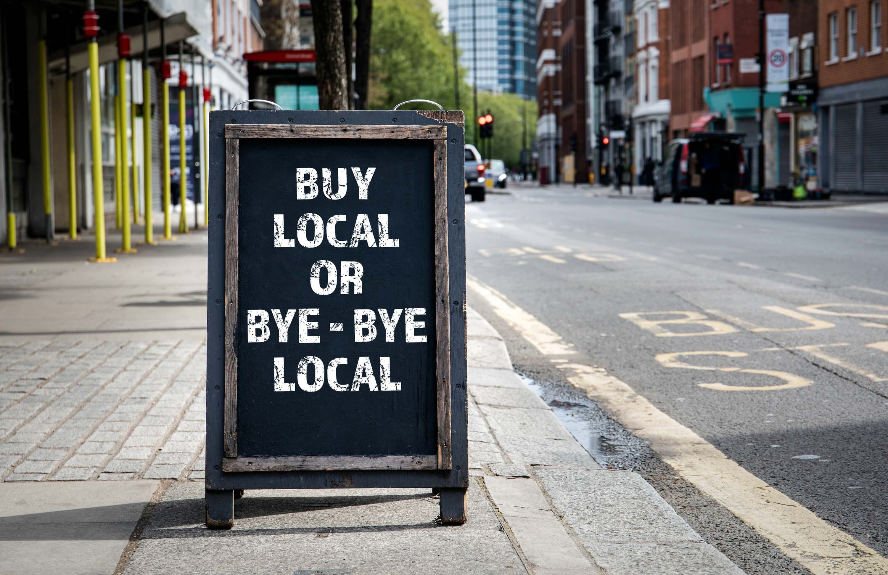 Street sign promoting local shopping with 'Buy Local or Bye-Bye Local' message.