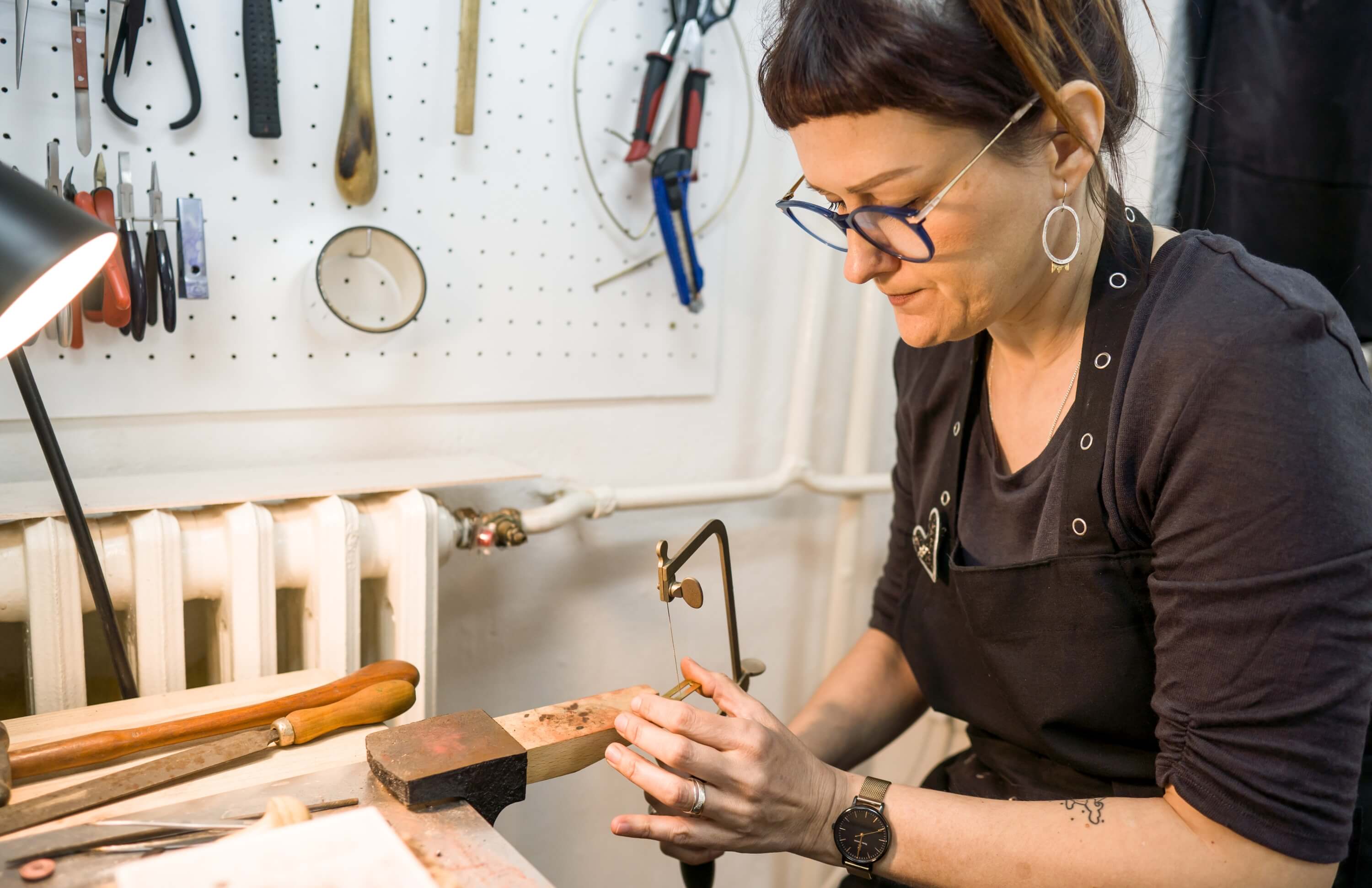 Jewelry maker working in a workshop, highlighting maker profiles and community building.