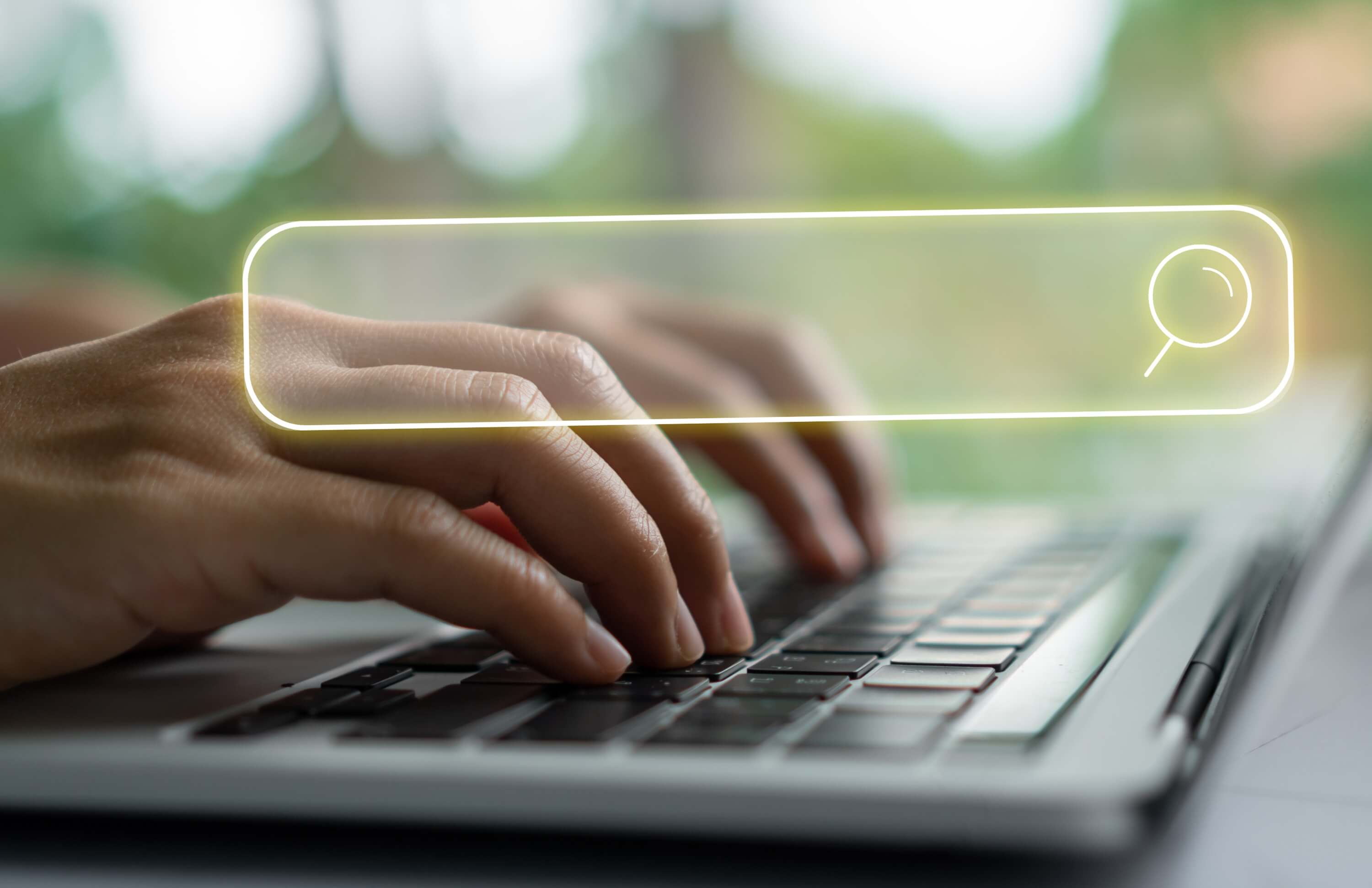 Hands typing on a laptop with a glowing search bar, representing advanced product filtering and search capabilities.