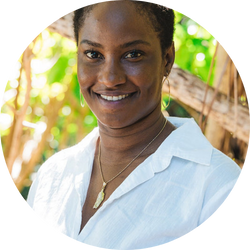 Sheba Manley, jewelry designer at SKF Shoppe, smiling outdoors in a white shirt.